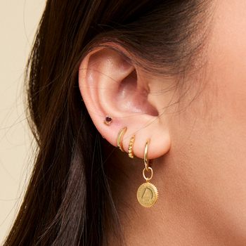 Ohio State Sunburst Earring Charm shown on figure in gold with the Florentine and Sunburst Hoop Earrings and the Garnet Stud in gold