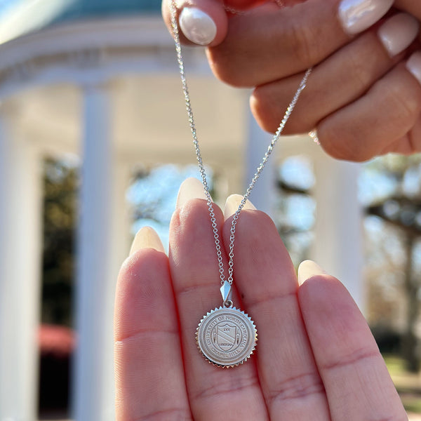 Sterling Silver UNC Sunburst Necklace in front of Old Well