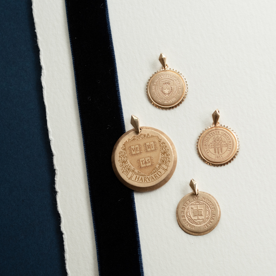 Gold Harvard University pendants on a white and navy background
