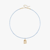 A delicate light blue beaded necklace with a small gold birdcage pendant, displayed on a clean white background.