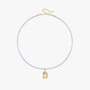 A delicate light blue beaded necklace with a small gold birdcage pendant, displayed on a clean white background.