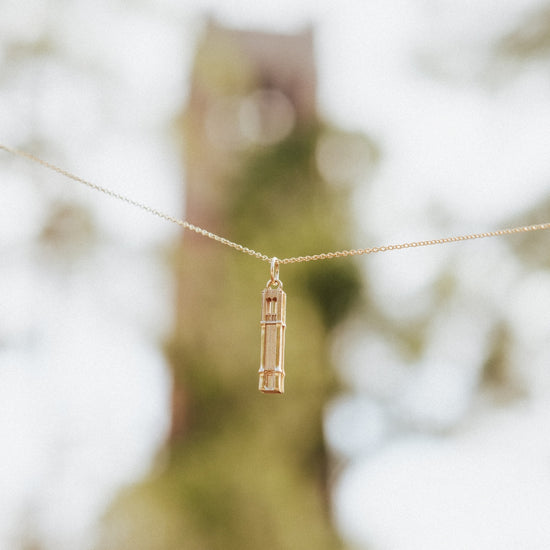Florida Century Tower Pendant shown on Cable Chain against blurred background of real Century Tower on Florida campus