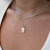 Close-up of a person wearing a gold necklace with a tag pendant on a white background