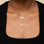 McDaniel College horizontal bar necklace shown on figure in Cavan Gold styled with a Sunburst Pendant, Emerald Gemstone and Cable Chain. 