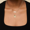 McDaniel College horizontal bar necklace shown on figure in Cavan Gold styled with a Sunburst Pendant, Emerald Gemstone and Cable Chain. 