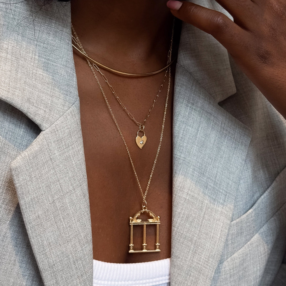 North Star Heart Lock Charm shown on figure in gold on Link Chain with Neck Collar and UGA Large Arch Pendant on Cable Chain