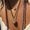 Notre Dame Logo Charm shown on figure on Link Chain with Large Notre Dame Florentine Pendant on Emerald Bead Chain with Blue Beads