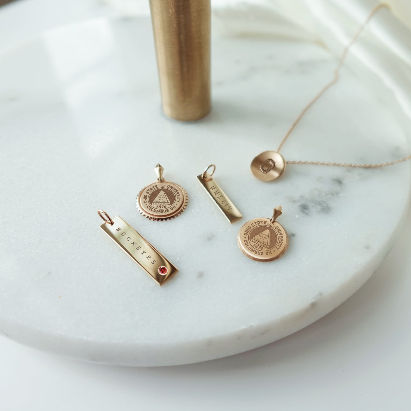 Ohio State collection featuring the Buckeyes Garnet Bar, Ohio State Sunburst, 2024 Bar, Ohio State Florentine, and Ohio State O Organic Necklace Petite laydown shown in gold