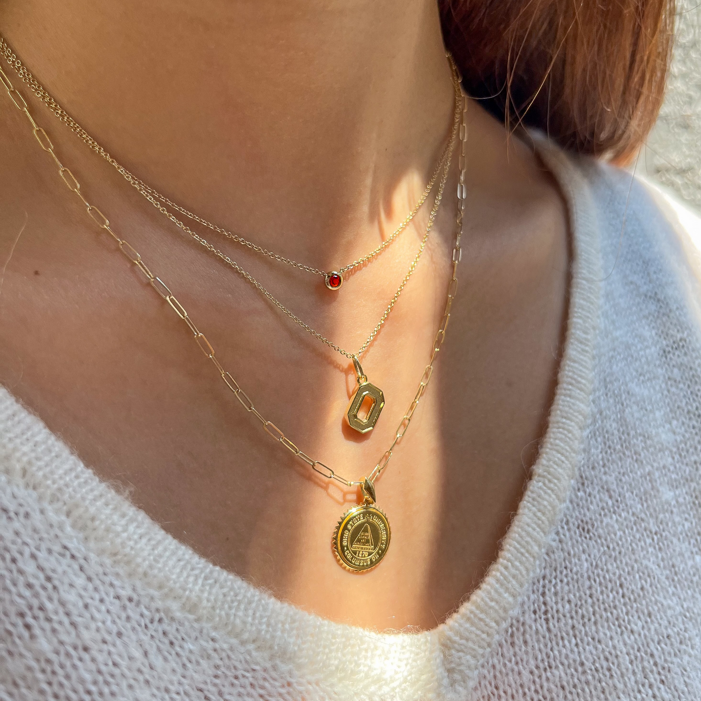 Ohio State O Letter Charm shown on figure in gold on Cable Chain with Ohio State Sunburst on Link Chain with Garnet Necklace