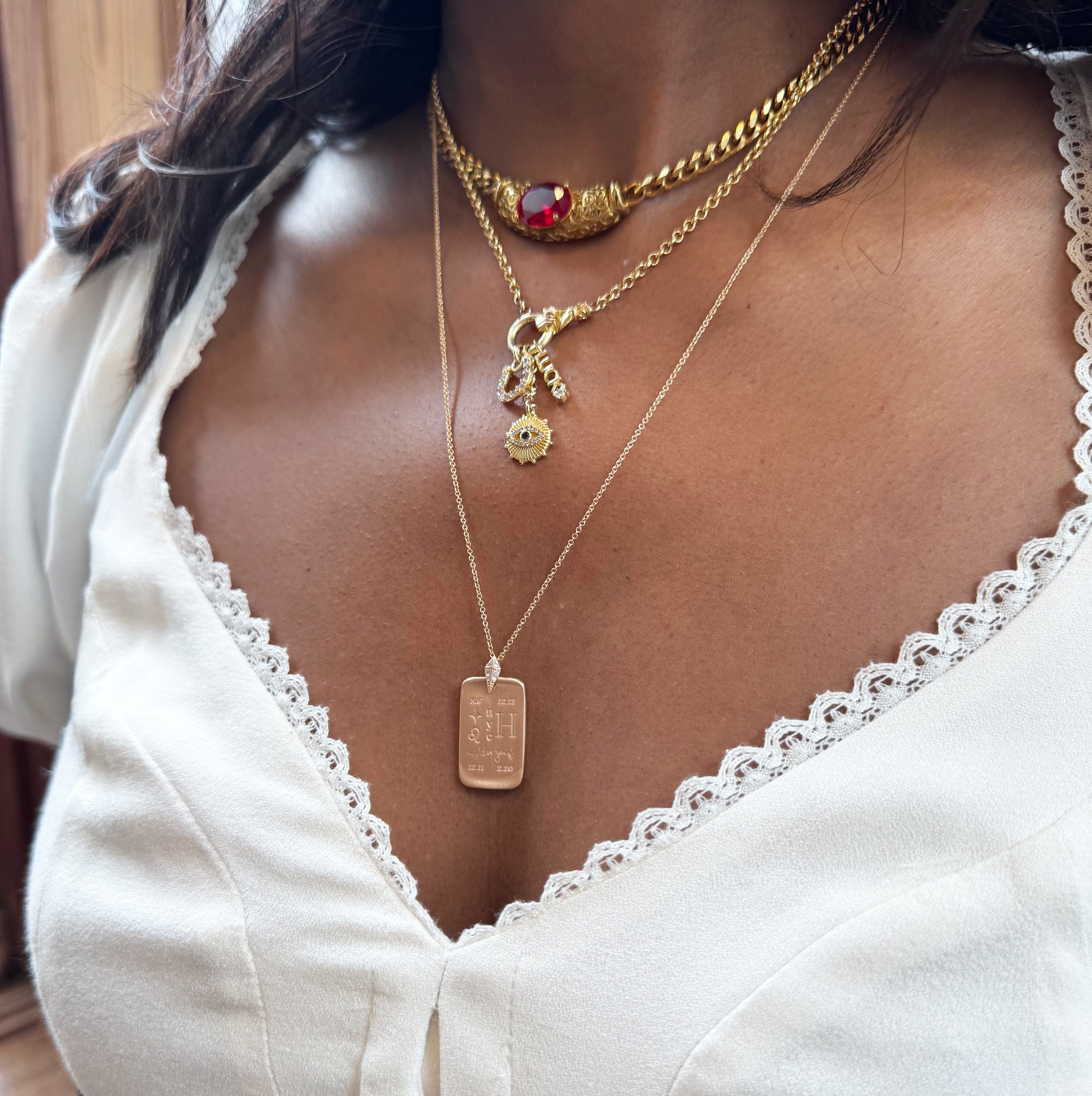 Close-up of a woman wearing multiple gold necklaces with pendants.