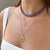 Close-up of a person wearing multiple necklaces with a focus on a gold coin pendant.
