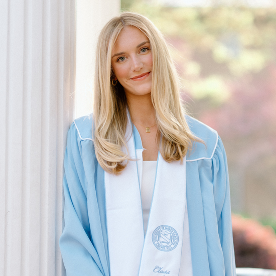 Woman in a light blue graduation gown with a white background