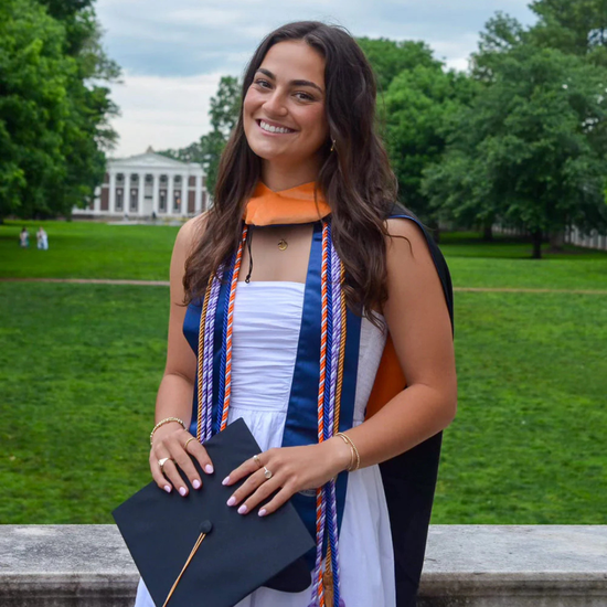 Graduate holding a diploma with a campus in the background