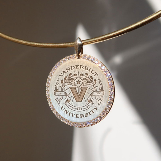 Vanderbilt University pendant on a gold chain against a neutral background