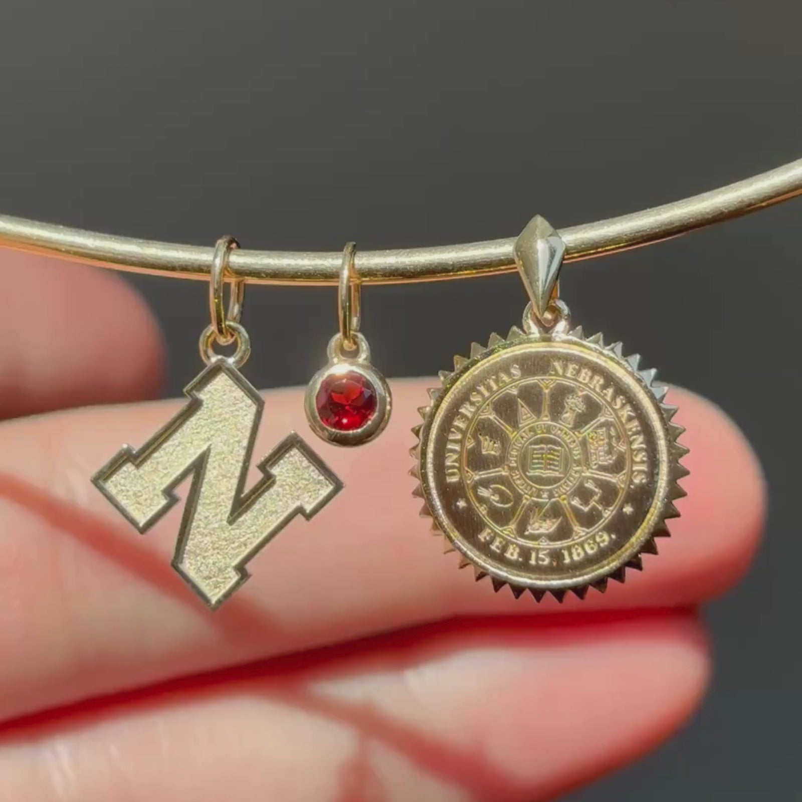 Nebraska Logo Charm, Garnet Gemstone, and Nebraska Sunburst Pendant shown in gold on Neck Collar